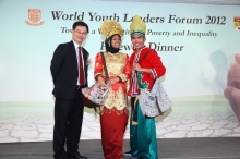 Prof. Chan Wood-yee (left), Associate Head of Shaw College, presents a pair of shoulder bags filled with Hong Kong features to the fabulously-dressed Malaysian couple as the prizes of the Best National Costume Award.