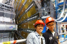 MPhil student Tsui Ka Ming and undergraduate student Tam Pok Ho in front of the ATLAS detector.  Both will be working the entire summer at CERN.