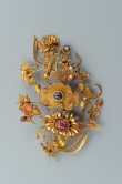 Gold Leisi Filigree Hairpin with Lotus and Shen Instrument Design and Precious Stone Inlay
Qing dynasty (1644–1912)
Length 13.8cm, weight 54.5g
Chengxuntang collection
The filigree hairpin heads comprise lotuses with buds, leaves and pods, having inlays of pearls and gems, beading edges and ribbed veins. In addition to the vegetative motifs, there is a sheng (mouth organ) with a beetle-like insect next to it. All the components are attached to gold wires and bundled together. The Lian (lotus) and Sheng form a pun for “consecutive promotions”. The beetle is a symbol for riches. The design, therefore, bequeaths a promising and lucrative career as an official.